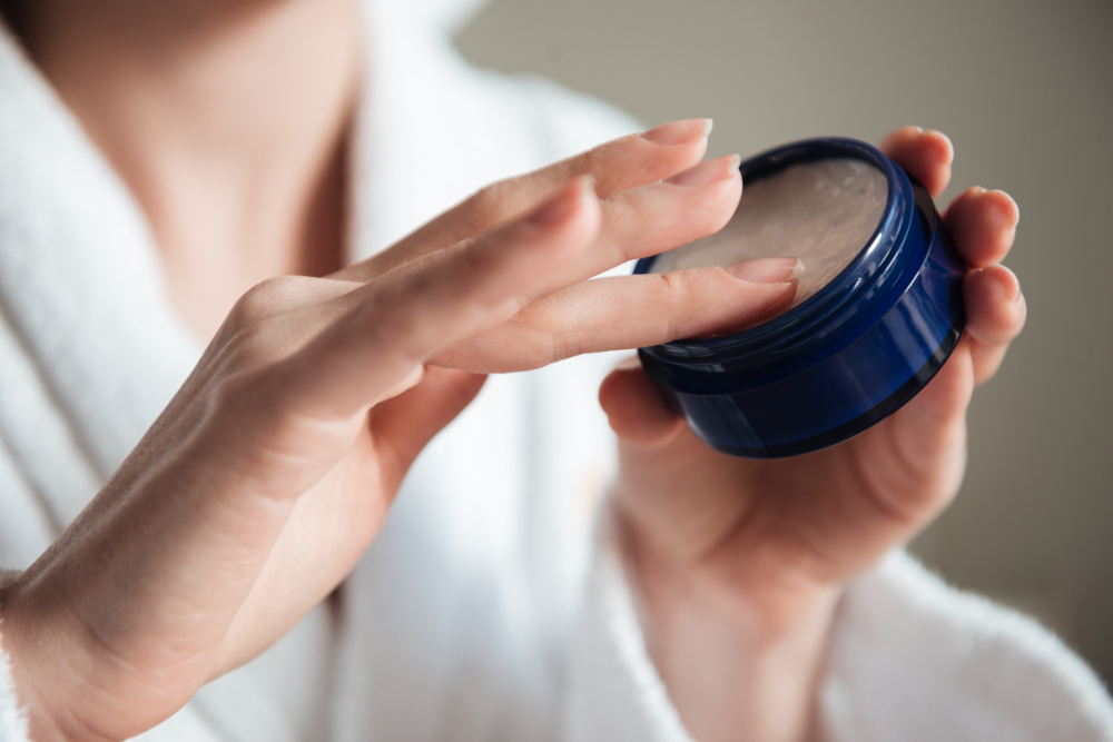 Manos abriendo un tarro de crema de cosmética coreana