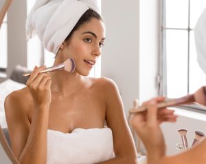 Mujer con toalla en el pelo preparando su piel antes de maquillarse