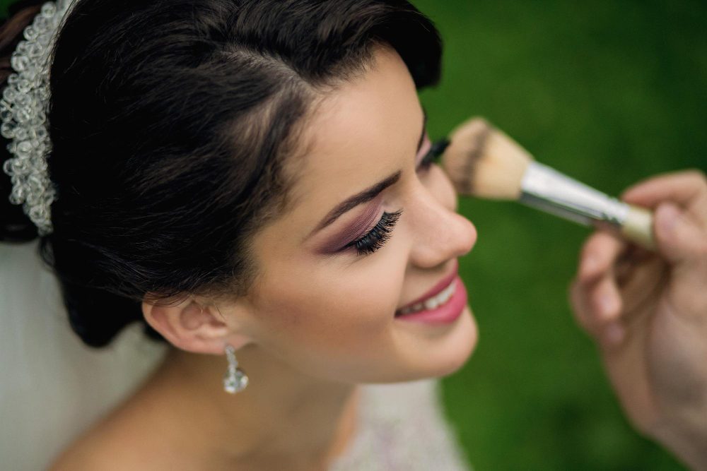 Novia con tocado recibiendo los últimos retoques de maquillaje