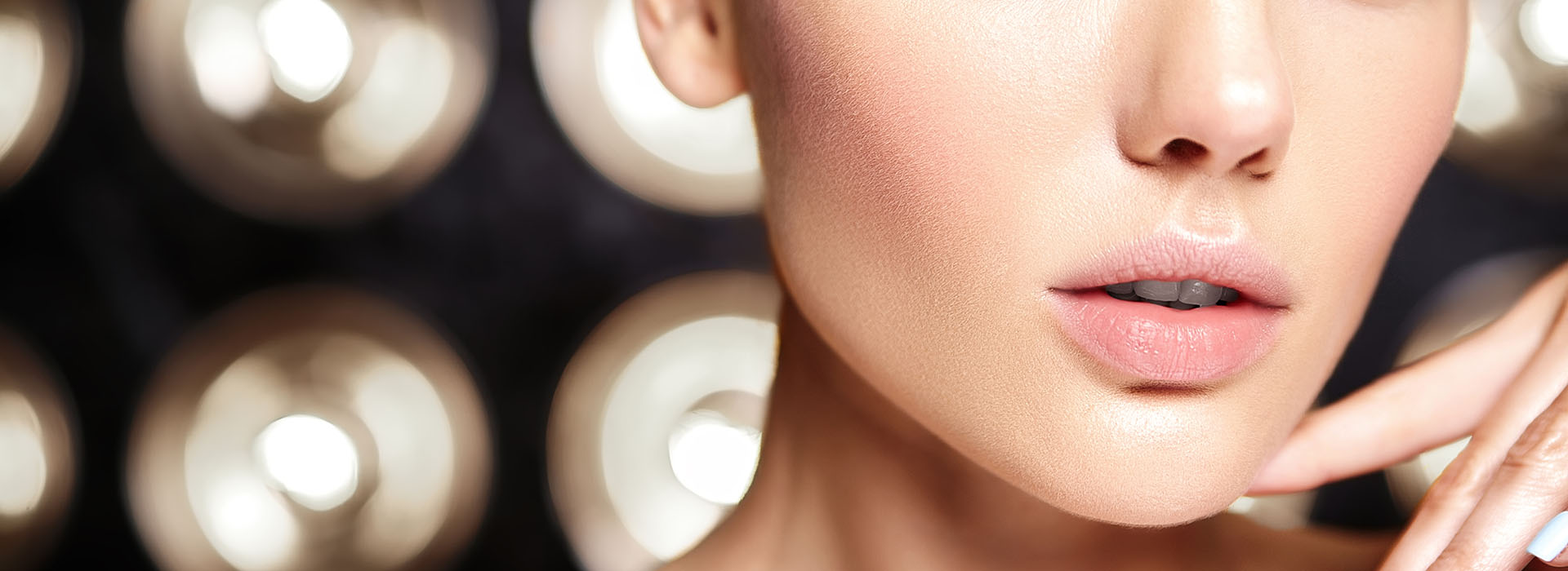 Rostro femenino con base de maquillaje bajo luces de tocador