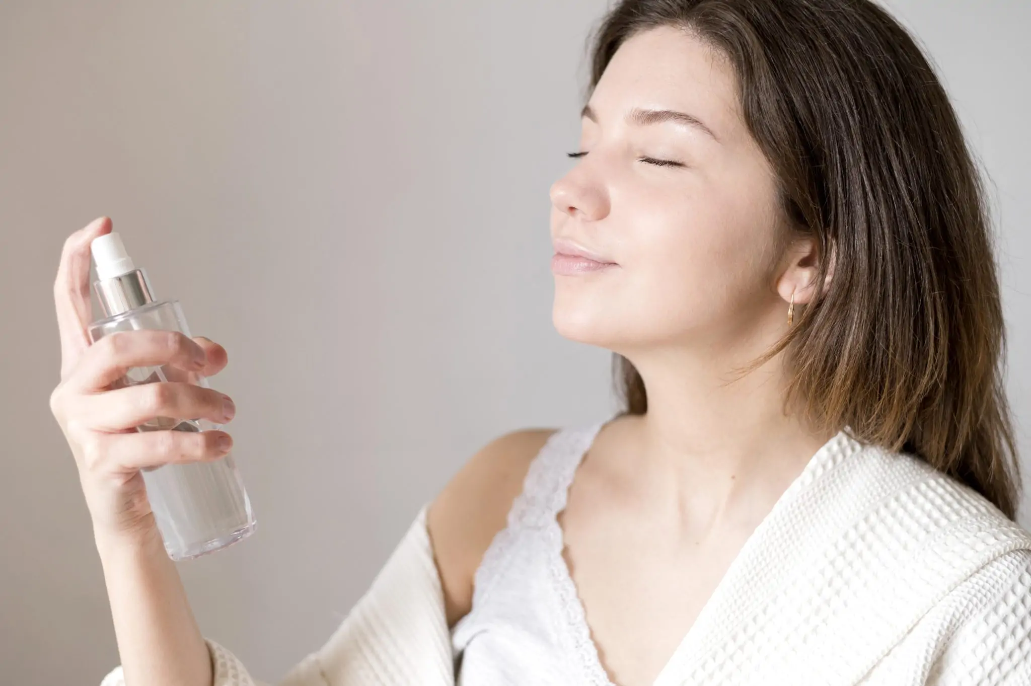 Mujer aplicándose spray fijador de maquillaje sobre el rostro