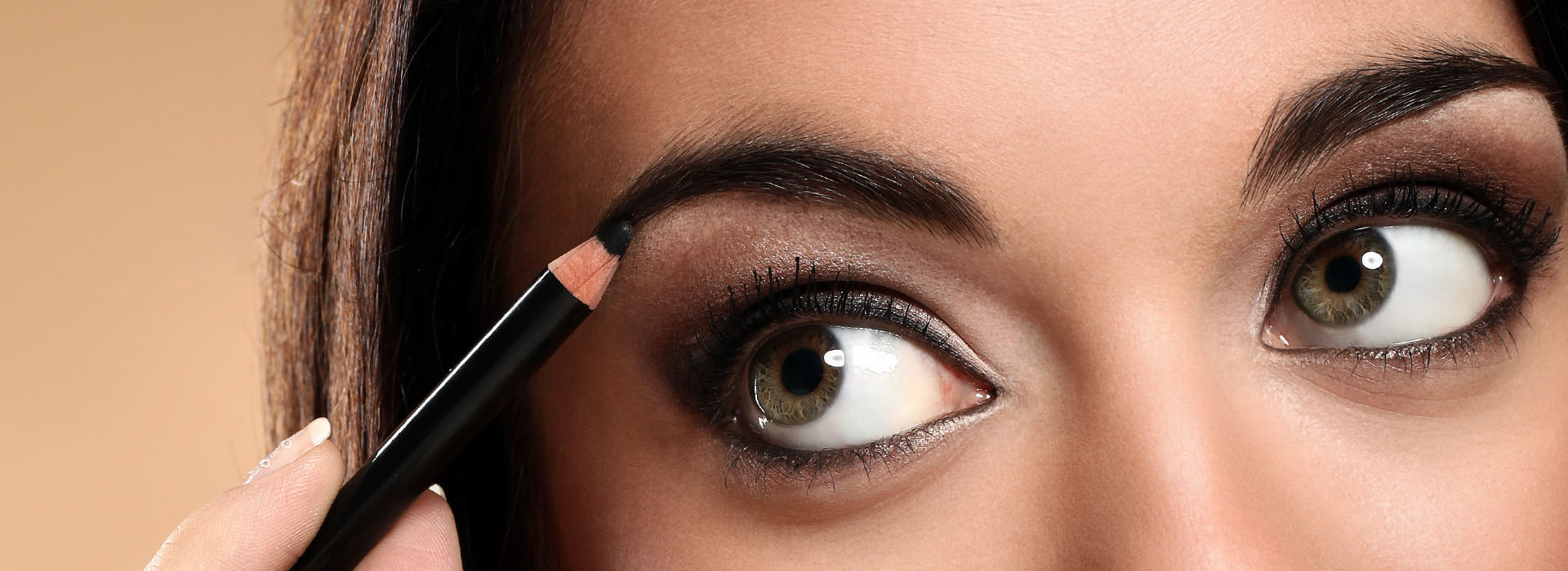 Perfilado de cejas con un lápiz sobre unos ojos marrones