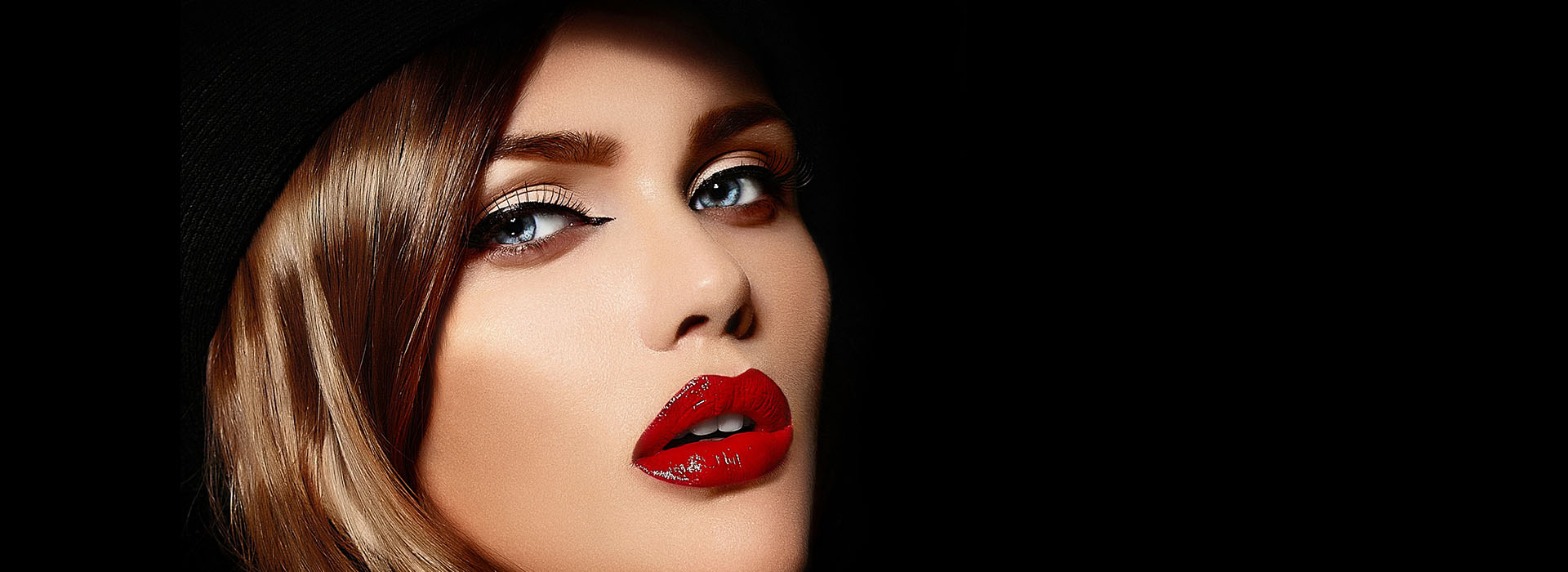 Mujer con maquillaje de fiesta y labios rojos sobre fondo negro