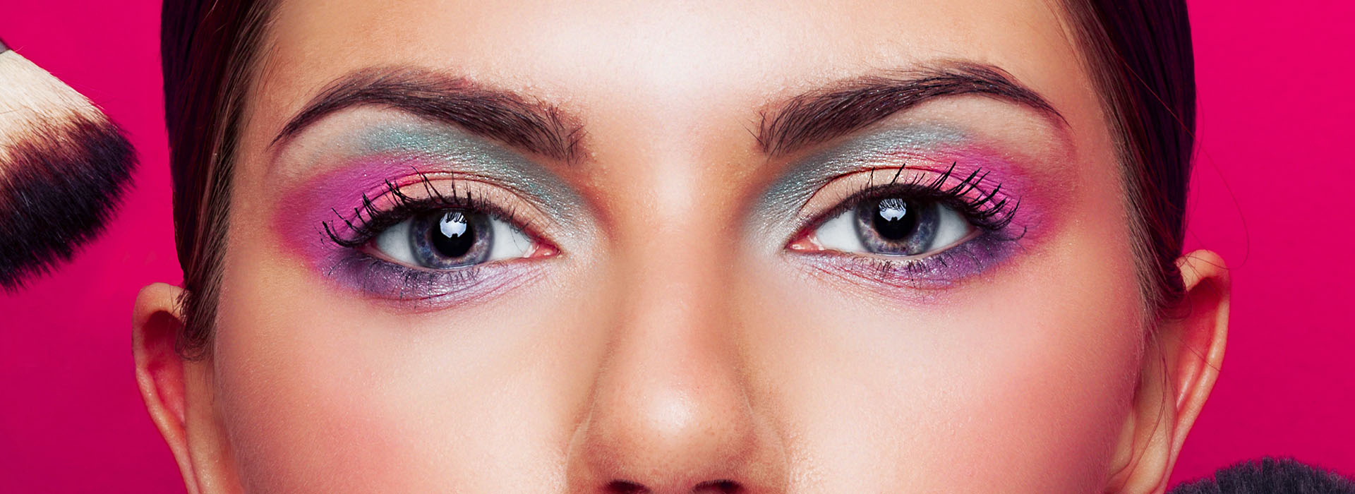 Ojos maquillados en tonos rosas sobre fondo fucsia