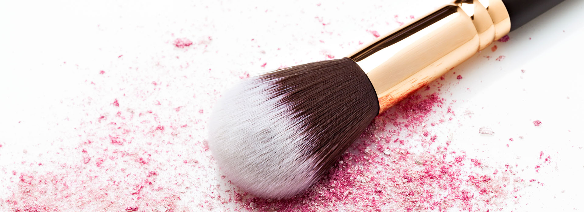 Brocha de maquillaje sobre polvos minerales de tono rosado